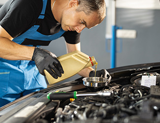 tech pouring oil into engine