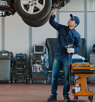 Skilled BMW Service technician with handheld computer and wearing gray BMW Service jumpsuit