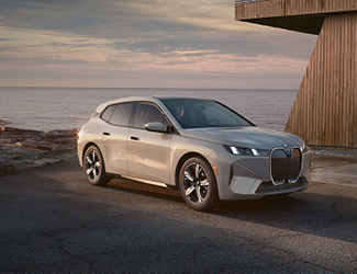 Gray BMW SUV driving though water on a beach