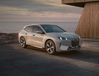 Gray BMW SUV driving though water on a beach