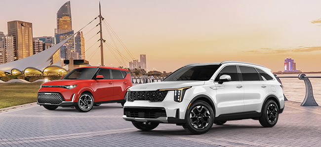 Two cars by the ocean with a city in the back - Shop at Crown Kia