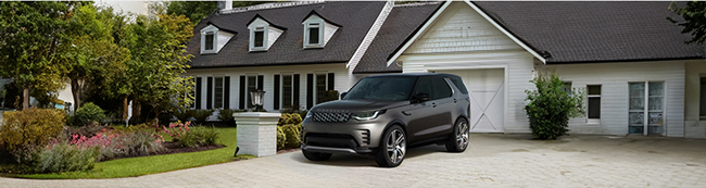 A gray Land Rover parked in the driveway of a house