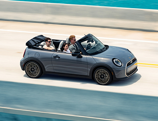 A convertible MINI driving on a bridge